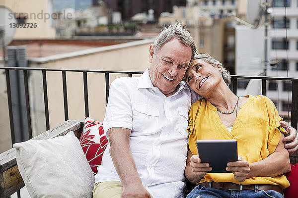 Liebevolles älteres Ehepaar sitzt auf einer Bank auf der Terrasse