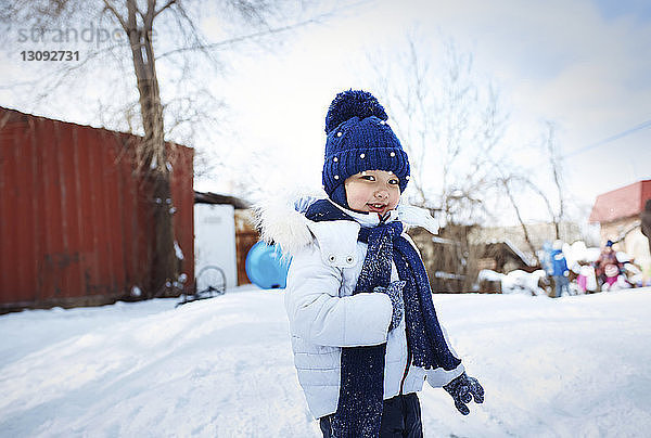 Porträt eines niedlichen Mädchens in warmer Kleidung  das auf einem verschneiten Feld steht