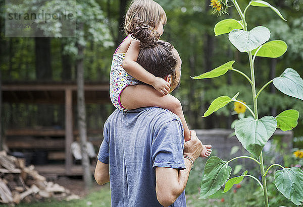 Glücklicher Vater trägt Mädchen auf den Schultern im Hinterhof