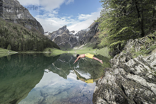 Seitenansicht eines Mannes ohne Hemd  der gegen die Berge in den See taucht