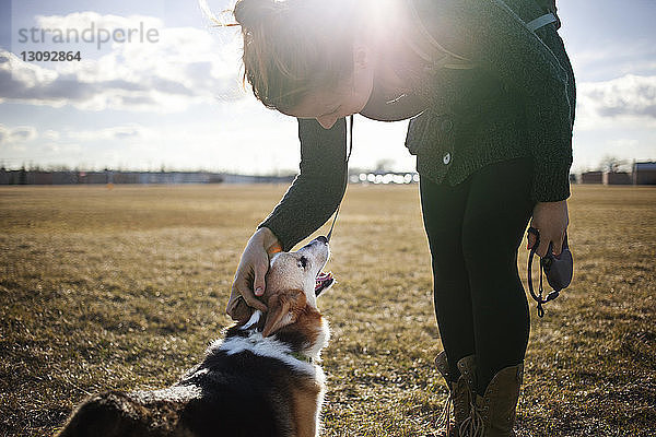 Frau spielt mit Hund auf dem Feld gegen den Himmel an einem sonnigen Tag