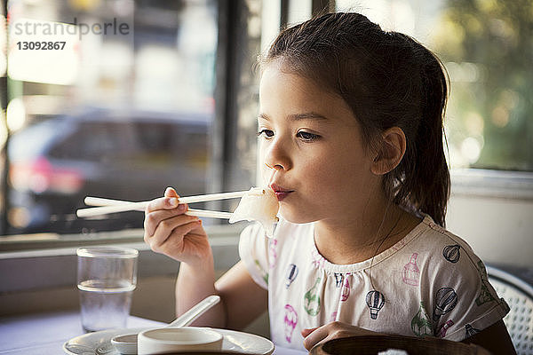 Mädchen bläst heiße Knödel  während sie im Restaurant sitzt