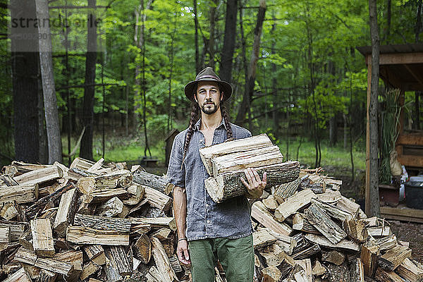 Porträt eines Mannes mit Brennholz im Wald