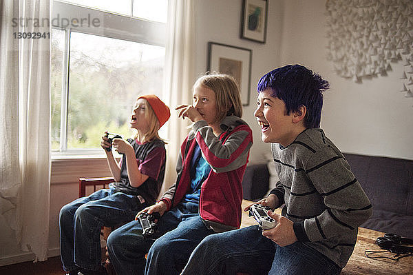 Jungen  die zu Hause auf dem Bett sitzend Videospiele spielen