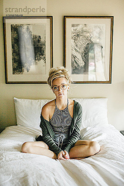 Porträt einer Frau  die zu Hause auf dem Bett sitzt