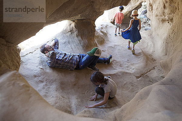 Vater entspannt sich  während die Kinder in der Höhle spielen