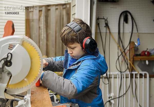 Junge mit Gehörschutz bei der Arbeit im Garten