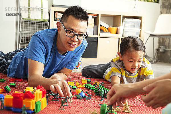 Vater und Kinder spielen zu Hause mit Spielzeug auf dem Boden