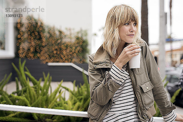 Nachdenkliche junge Frau trinkt Kaffee im Freien