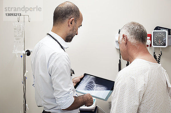 Arzt zeigt dem Patienten im Krankenhaus Röntgenberichte im Tablet-Computer