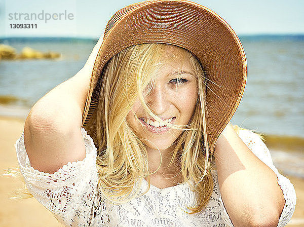 Porträt einer lächelnden Frau mit Sonnenhut am Strand
