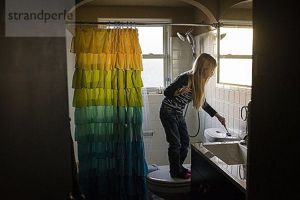 Mädchen  das im Badezimmer mit der Toilettenbürste spült