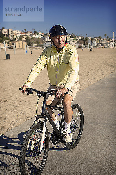 Mann fährt Fahrrad auf Straße gegen klaren blauen Himmel