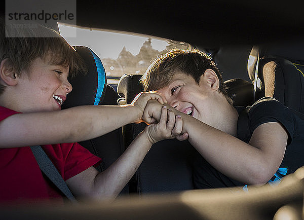 Fröhliche Brüder spielen während der Fahrt im Auto