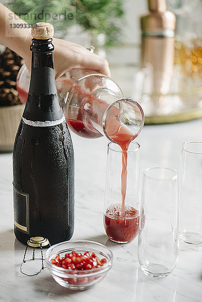 Ausgeschnittenes Bild einer Frau  die zu Hause Saft in ein Glas gießt