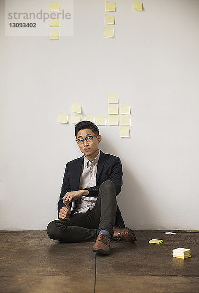 Porträt eines selbstbewussten Geschäftsmannes  der im Kreativbüro an der Wand sitzt