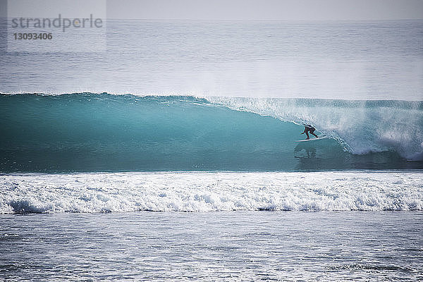 Person surft in rollender Brandung auf den Mentawai-Inseln