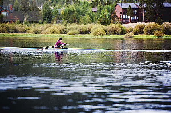 Seitenansicht einer Frau beim Kajakfahren auf einem See bei Bäumen