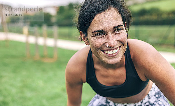 Glückliche Frau beugt sich beim Sport im Park