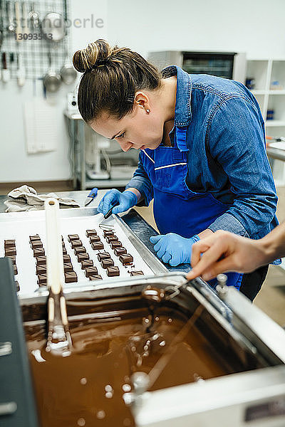 abgeschnittene Hand des Kochs  der während der Arbeit mit einem Kollegen in der Fabrik Schokolade in Fondue taucht