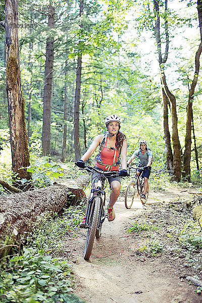 Fahrrad fahrendes Paar auf unbefestigter Straße im Wald
