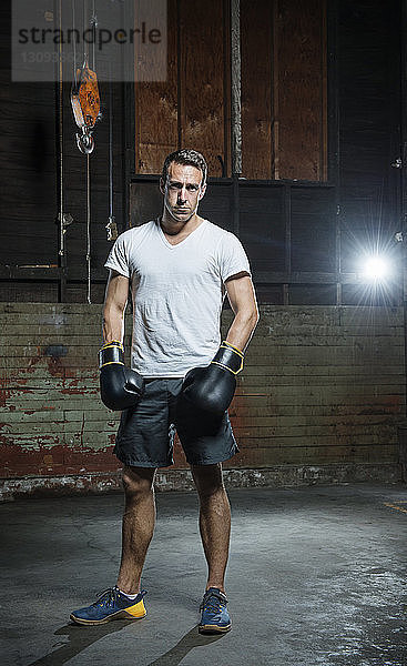 Porträt eines selbstbewussten männlichen Boxers in voller Länge im Fitnessstudio