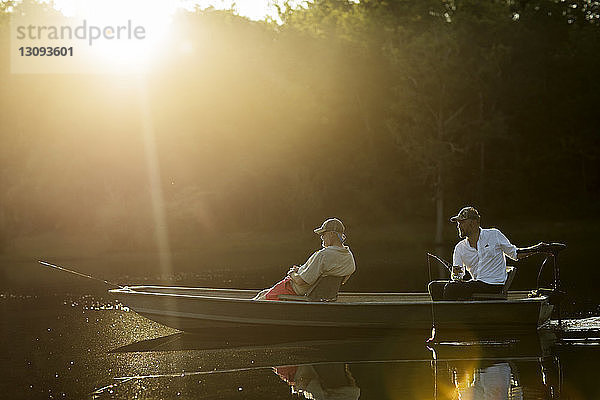 Freunde sitzen im Ruderboot beim Angeln auf dem See
