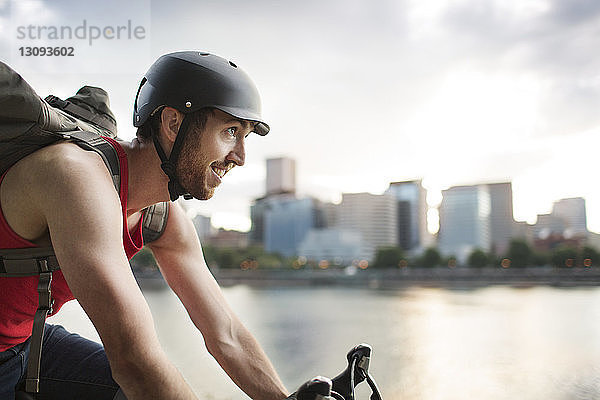 Glücklicher Mann fährt Fahrrad am See in der Stadt
