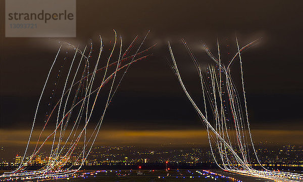 Lichtgemälde über dem Flughafen vor bewölktem Himmel in der nächtlichen Stadt