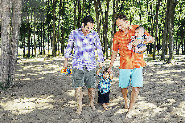 Homosexuelles Coupé mit Söhnen am Strand spazieren