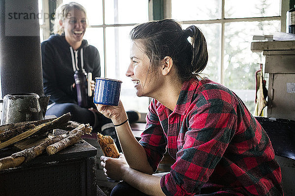 Frauen lachen beim Trinken in der Hütte