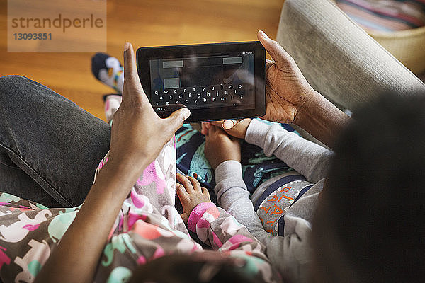 Draufsicht eines Vaters  der einen Tablet-Computer mit Kindern zu Hause benutzt