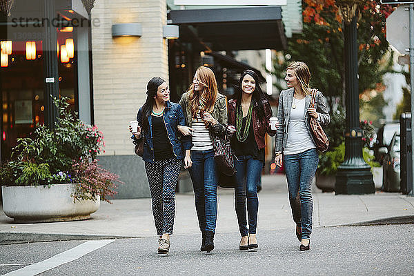 Glückliche Freundinnen unterhalten sich beim Gehen auf der Straße