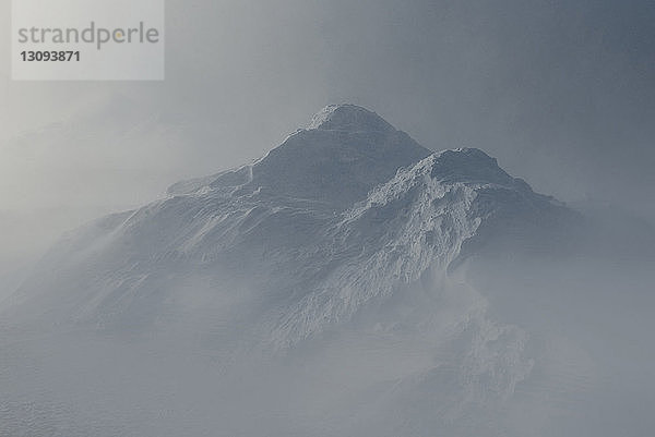 Idyllische Aussicht auf schneebedeckte Berge bei nebligem Wetter