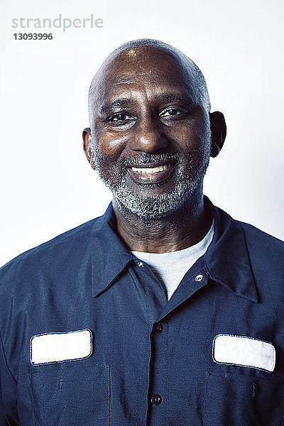 Porträt eines glücklichen älteren männlichen Arbeiters vor weißem Hintergrund