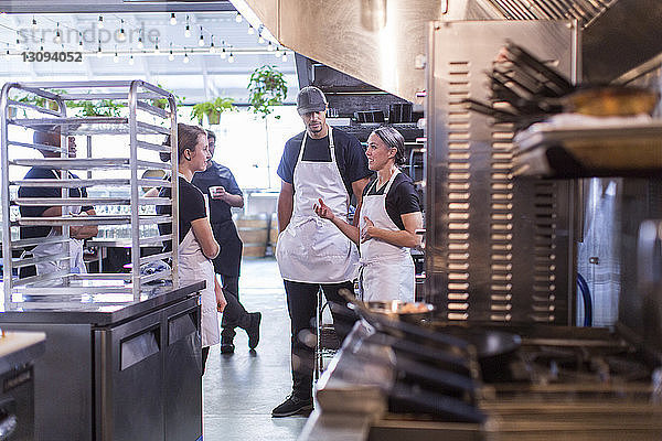 Köchin diskutiert mit Mitarbeitern in Restaurantküche