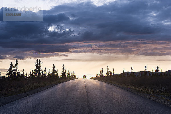 Straße mitten auf dem Feld im Denali-Nationalpark und Schutz gegen den Himmel bei Sonnenuntergang
