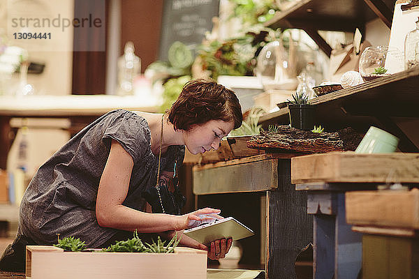 Arbeitnehmerin benutzt Tablet-Computer bei der Untersuchung von Pflanzen im Gartencenter