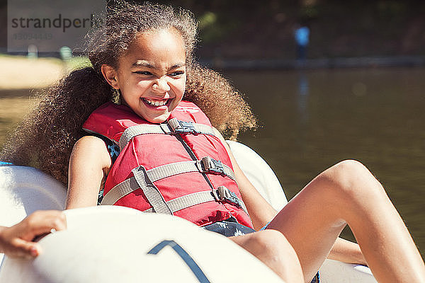 Glückliches Mädchen sitzt an einem sonnigen Tag im Tretboot
