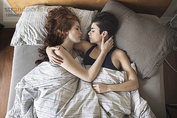 Hochwinkelansicht eines romantischen lesbischen Paares  das sich im Bett betrachtet