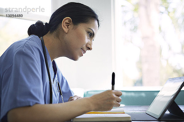 Seitenansicht einer Ärztin  die einen Tablet-Computer verwendet  während sie in einer medizinischen Klinik arbeitet