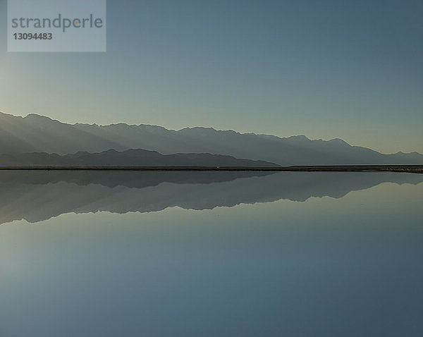 Symmetrische Ansicht des Mono-Sees durch Berge gegen klaren Himmel bei Sonnenuntergang
