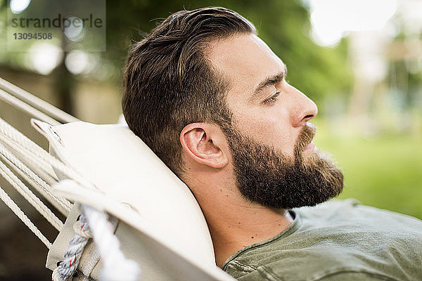 Seitenansicht eines Mannes  der sich auf einer Hängematte im Hof entspannt