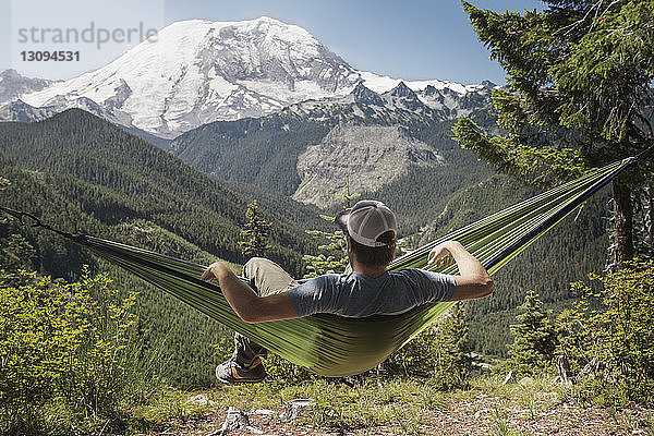 Mann liegt auf Hängematte gegen Mount Rainier