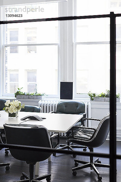 Leere Stühle um den Konferenztisch gegen die Fenster im Büro