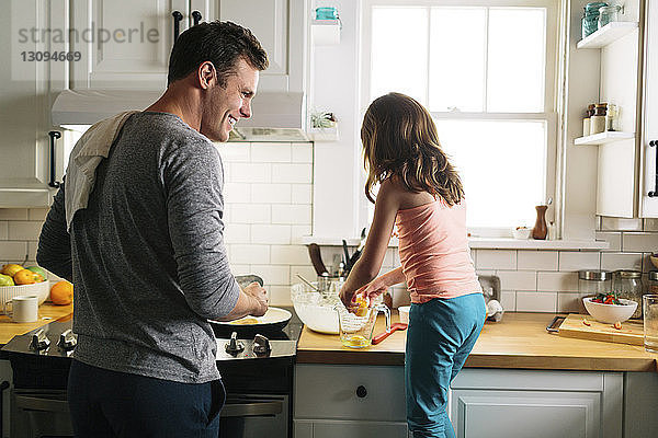 Glückliche Vater und Tochter bereiten zu Hause in der Küche Essen zu