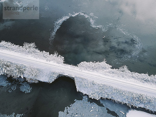Hochwinkel-Distanzansicht einer Person  die im Winter auf einem See paddelt