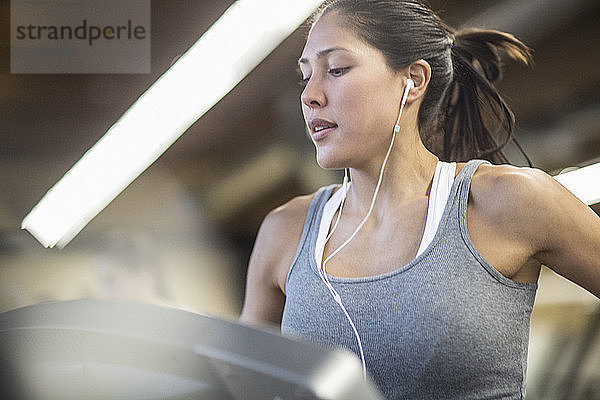 Selbstbewusste Frau  die Musik hört  während sie im Fitnessstudio auf dem Laufband trainiert