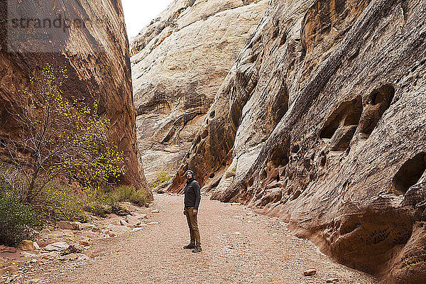 Wanderer steht inmitten der Berge im Monument Valley