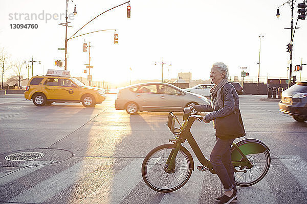 Seitenansicht einer älteren Frau  die mit dem Fahrrad auf der Straße geht
